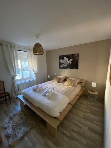 un grand lit blanc dans une chambre avec une fenêtre dans l'établissement Gite comme chez soi Ducey les Chèris, à Ducey