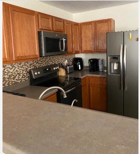 a kitchen with a black refrigerator and wooden cabinets at Cozy5star in Killeen
