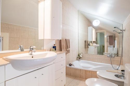a white bathroom with a sink and a tub at Casa dos Castanheiros in Camacha