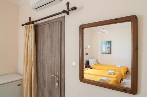 a mirror reflecting a bedroom with a yellow bed at Holiday Beach Resort Santorini in Perivolos
