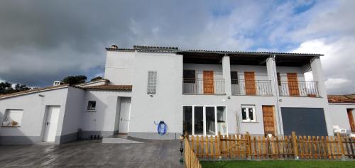 ein weißes Haus mit einem Holzzaun davor in der Unterkunft Casa Rural A la Vera de Monfrague in Tejeda de Tiétar
