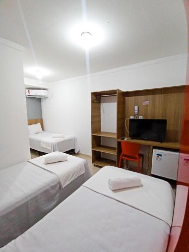een hotelkamer met 2 bedden en een televisie bij HOTEL PINHEIRO CENTER in Pinheiro