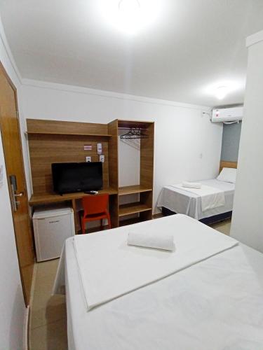 een kleine kamer met 2 bedden en een televisie bij HOTEL PINHEIRO CENTER in Pinheiro