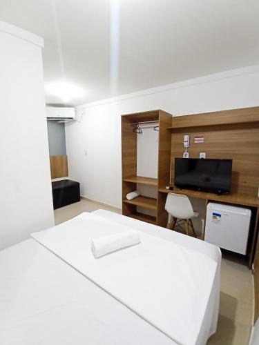 een slaapkamer met een bed, een bureau en een televisie bij HOTEL PINHEIRO CENTER in Pinheiro