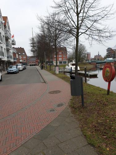 a red brick sidewalk next to a river with buildings at Maje Am alten Binnenhafen in Emden