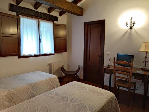 a bedroom with two beds and a desk and a window at Pasaje San Jorge in Comillas