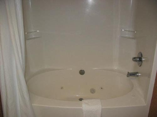 a bathroom with a bath tub with a white shower curtain at Holiday Inn Express Hotel & Suites Laurinburg, an IHG Hotel in Laurinburg
