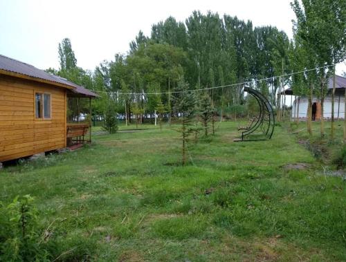 a yard with a tree and a swing at Гостевой дом Темирлан in Kegeti