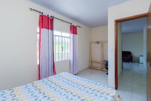 a bedroom with a bed with red and blue curtains at Sobrado da Vila, 1km Centro, ideal Trabalho e Passeio in Morretes