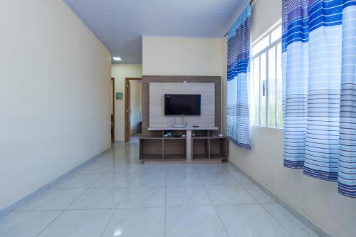 a living room with a television and a tiled floor at Sobrado da Vila, 1km Centro, ideal Trabalho e Passeio in Morretes