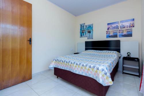 a bedroom with a bed and a wooden door at Sobrado da Vila, 1km Centro, ideal Trabalho e Passeio in Morretes