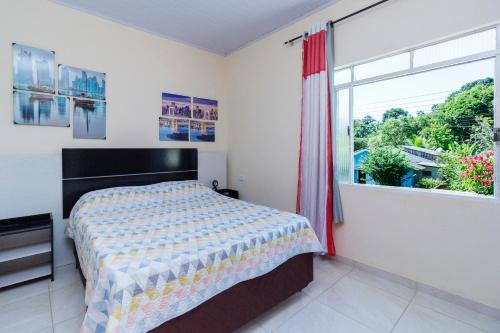 a bedroom with a bed and a large window at Sobrado da Vila, 1km Centro, ideal Trabalho e Passeio in Morretes