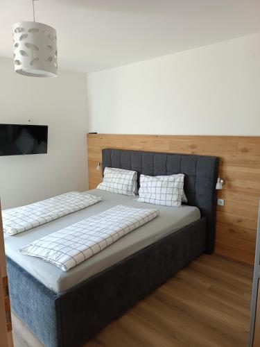 a bedroom with a large bed with a wooden headboard at Frühstückspension Lemberger in Dellach im Drautal