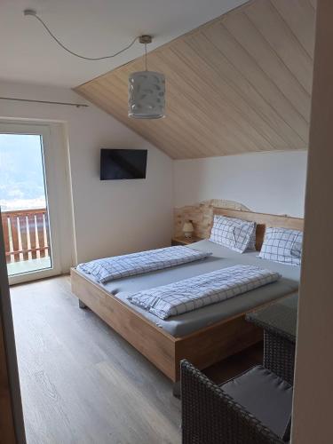 a bedroom with a large bed and a balcony at Frühstückspension Lemberger in Dellach im Drautal