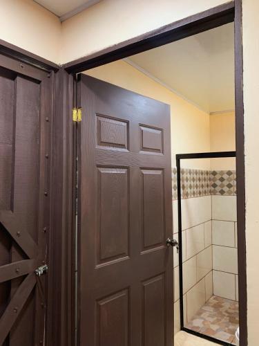 a bathroom with a brown door and a shower at Hospedaje La Naciente in Turrialba