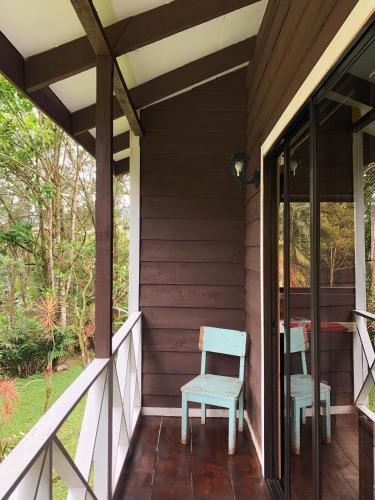 a porch of a house with two chairs on it at Hospedaje La Naciente in Turrialba