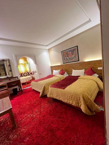 a bedroom with two beds and a red carpet at Hotel Kasbah Asmaa in Midelt