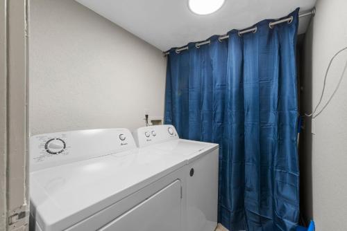 a bathroom with a washing machine and a blue shower curtain at Truist Park Comfort Stays in Atlanta