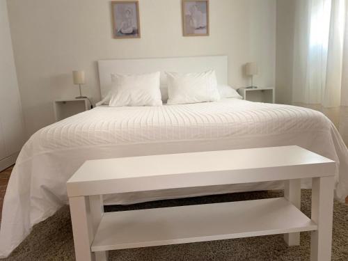un letto bianco con una panca bianca accanto di APARTAMENTO PLAZA ESPAÑA a Écija