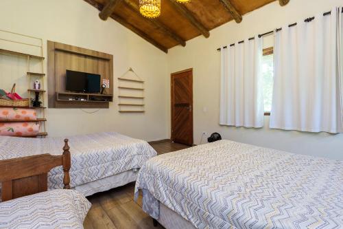 a bedroom with two beds and a flat screen tv at Recanto do sossego!! in Morretes