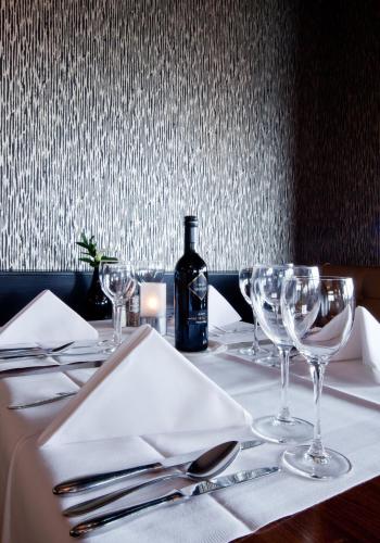 a table with glasses and a bottle of wine on it at Van der Valk Hotel Avifauna in Alphen aan den Rijn