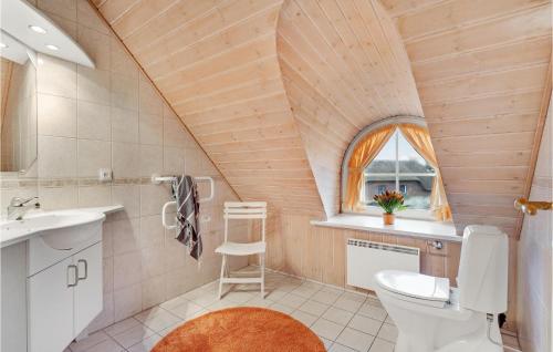 a bathroom with a toilet and a sink and a window at Cozy Home In Blvand With Sauna in Blåvand