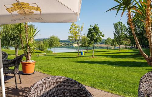 patio z krzesłami, parasolem i parkiem w obiekcie Ferienhaus Am Naturbadesee w mieście Königsdorf
