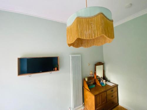 a room with a tv and a dresser and a chandelier at Ben A'an House in Callander