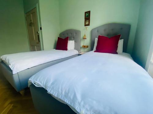 two beds with red pillows in a room at Ben A'an House in Callander