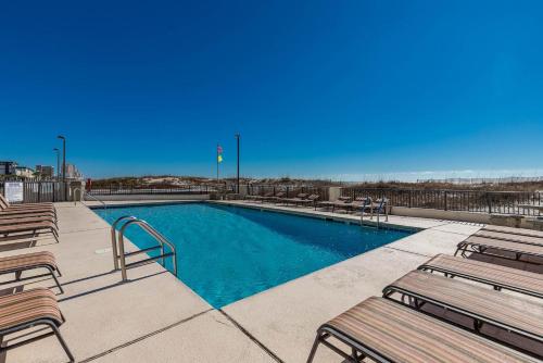 a swimming pool with wooden benches next to at Island Winds East by Brett Robinson Vacations in Gulf Shores