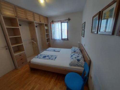 a small bedroom with a bed and a blue chair at Apartments Božena in Pakoštane