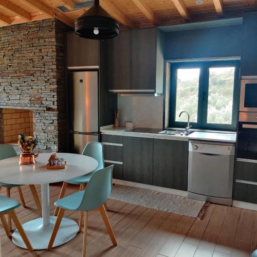 a kitchen with a table and chairs and a sink at Eira da Fraga in Vila Nova de Foz Coa