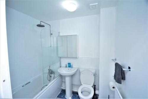 a white bathroom with a toilet and a sink at Spacious Two-Bedroom Apartment in Dagenham