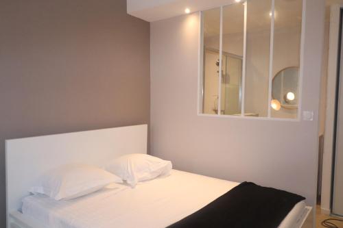 - un lit blanc avec des oreillers blancs et un miroir dans l'établissement Appartement au calme plein centre historique, à Montpellier
