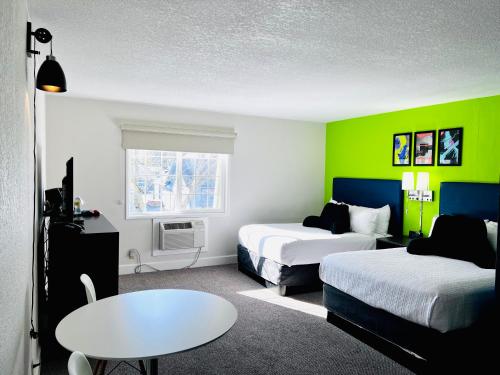 Habitación de hotel con 2 camas y mesa en Signature Inn Eugene en Eugene