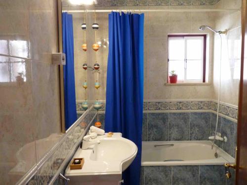 La salle de bains est pourvue d'un rideau de douche bleu, d'une baignoire et d'un lavabo. dans l'établissement Top Floor Ocean View Apartment – Near Beach Luz, à Luz