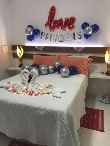 a bed with balloons and a sign that says love participants at AYRE GOSTOSO POUSADA in São Miguel do Gostoso