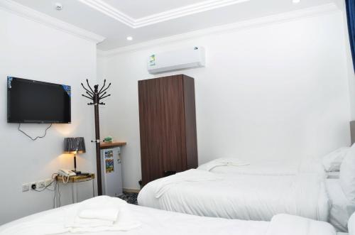 a bedroom with two beds and a tv on the wall at Luluat Al Badaie Hotel in Makkah