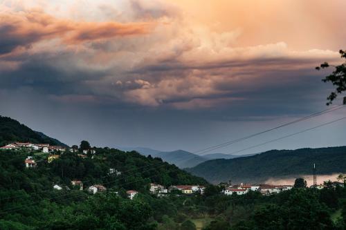 a cloudy sky over a hill with houses and trees at Vina Kobal, Kobal Family Estate in Štanjel