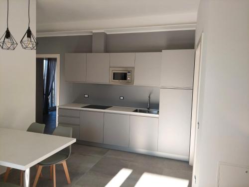 a kitchen with white cabinets and a white table at La Casa in Rivalta in Verduno