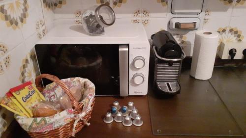 a counter top with a microwave and a basket of balls at Casa con piscina climatizada y barbacoa in Freigido