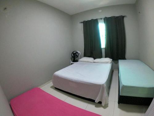 a bedroom with two beds and a window at Casa praia Família Barbosa, com piscina in Luis Correia