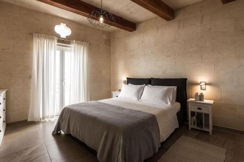 een slaapkamer met een groot bed en een raam bij The Muse Gozo Farmhouse with indoor and outdoor pool in Qala