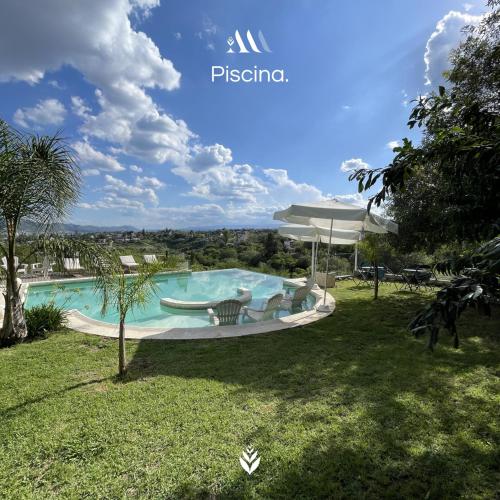 a swimming pool with chairs and an umbrella in a yard at Agrippina in Villa Carlos Paz