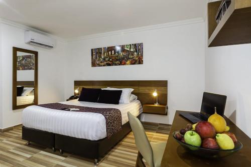 a hotel room with a bed and a bowl of fruit on a table at Hotel Vizcaya Plaza in Barrancabermeja