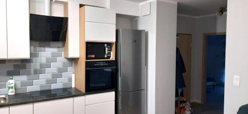 eine Küche mit einem Kühlschrank und einer Mikrowelle in der Unterkunft Apartament Bosman - Osiedle Beauforta, PARKING FREE in Pogórze