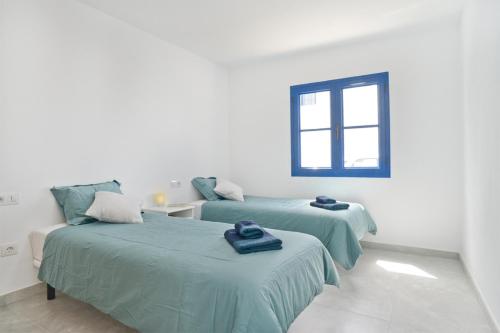 two beds in a white room with a window at Apartamento Dunas De Famara in Famara