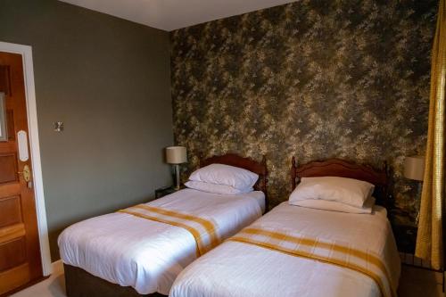 two beds in a hotel room with a wallpaper at The Ring Farmhouse in Birr