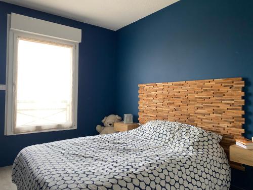 Dormitorio azul con cama y ventana en Appartement pour les 24 heures en Le Mans