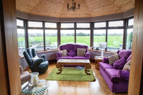 a living room with purple couches and a table at The Ring Farmhouse in Birr